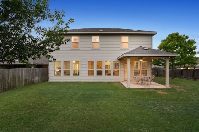 rear view of house featuring roof with shingles, a fenced backyard, a patio area, ceiling fan, and a yard