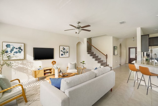 living room with stairway, arched walkways, visible vents, and light tile patterned floors