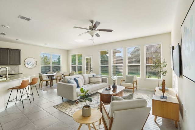 living area with baseboards, a ceiling fan, visible vents, and light tile patterned floors