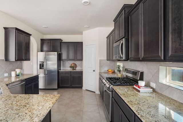 kitchen featuring backsplash, light stone countertops, and appliances with stainless steel finishes