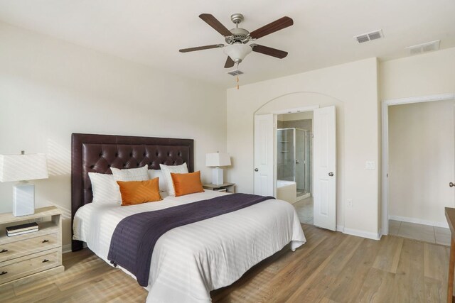 bedroom featuring ensuite bath, wood finished floors, and visible vents