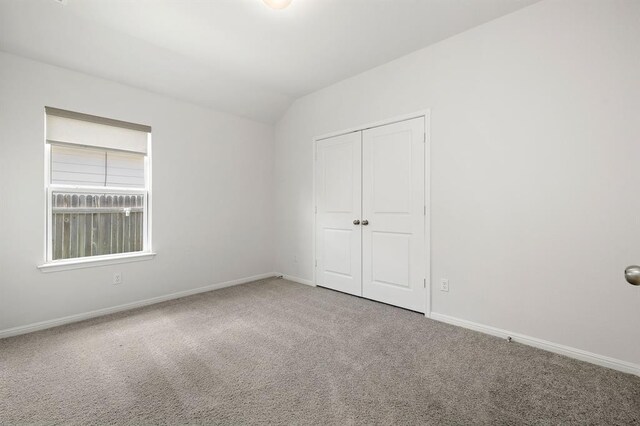 carpeted empty room with baseboards and lofted ceiling