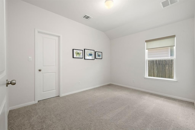 spare room with vaulted ceiling, carpet flooring, visible vents, and baseboards
