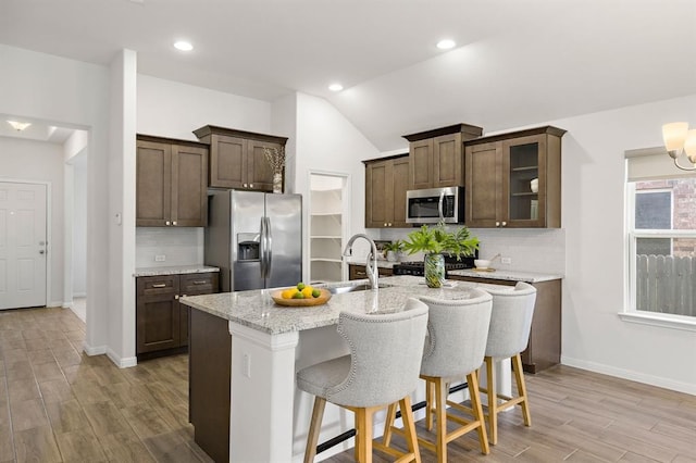 kitchen with vaulted ceiling, a sink, backsplash, and appliances with stainless steel finishes