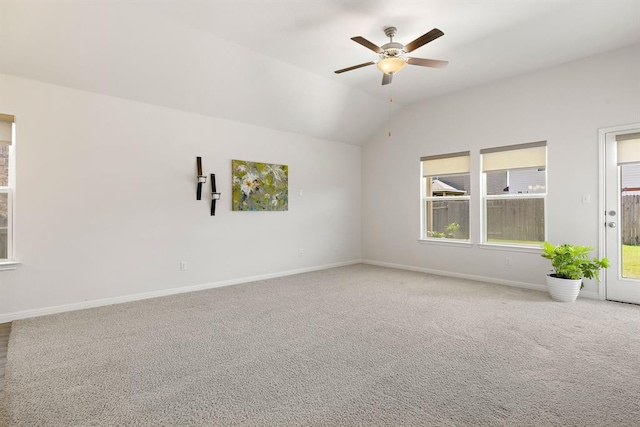 carpeted spare room with vaulted ceiling, a ceiling fan, and baseboards