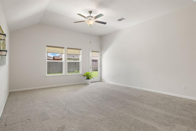 carpeted spare room with vaulted ceiling, visible vents, baseboards, and ceiling fan