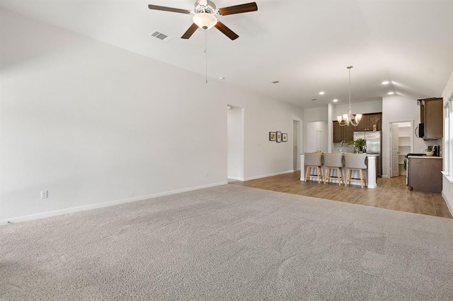 unfurnished living room featuring light carpet, baseboards, visible vents, recessed lighting, and ceiling fan with notable chandelier