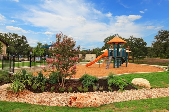 community jungle gym featuring fence and a lawn