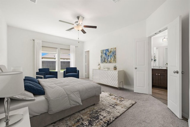 carpeted bedroom with a ceiling fan, ensuite bath, and baseboards