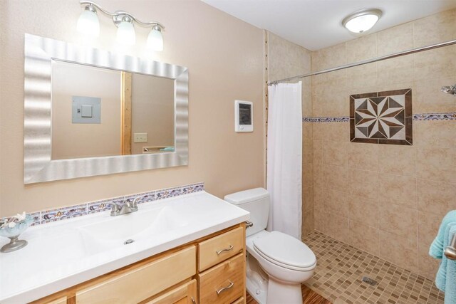 bathroom featuring a tile shower, toilet, and vanity