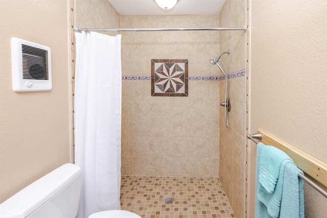 full bath featuring toilet, a textured wall, and a stall shower