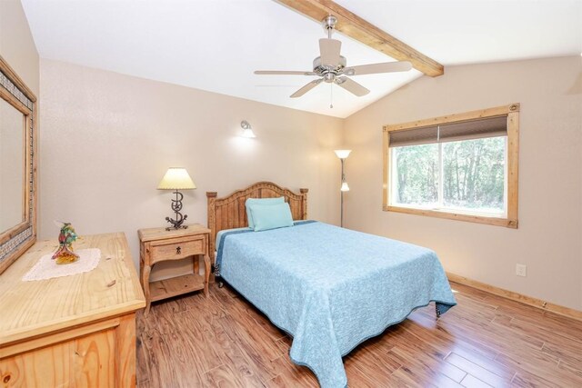 bedroom with ceiling fan, baseboards, wood finished floors, and vaulted ceiling with beams