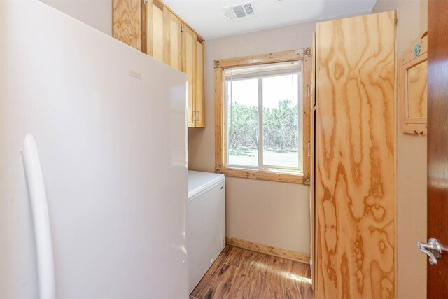 laundry room with cabinet space, light wood finished floors, baseboards, washer / clothes dryer, and visible vents