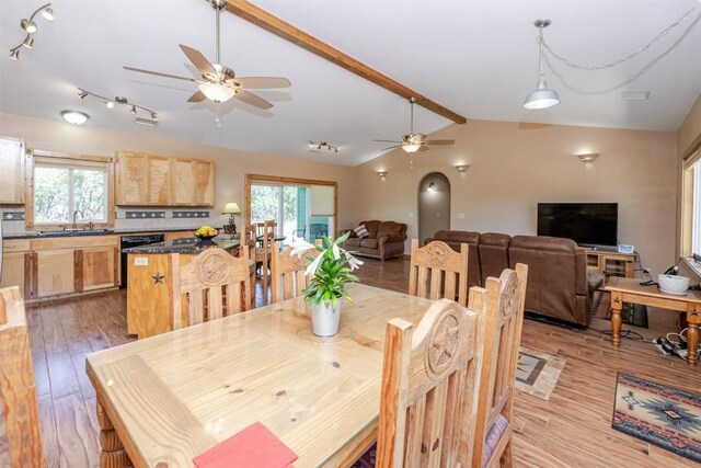 dining area featuring a ceiling fan, a healthy amount of sunlight, vaulted ceiling with beams, and light wood-type flooring