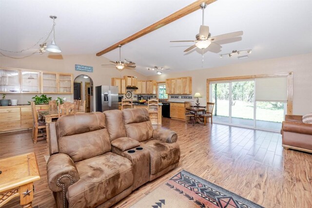 living room featuring arched walkways, light wood-type flooring, vaulted ceiling with beams, visible vents, and a ceiling fan