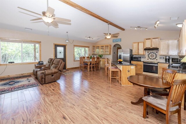 interior space with light wood-style floors, a wealth of natural light, lofted ceiling with beams, and ceiling fan