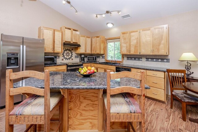 kitchen featuring vaulted ceiling, decorative backsplash, light brown cabinetry, stainless steel appliances, and visible vents
