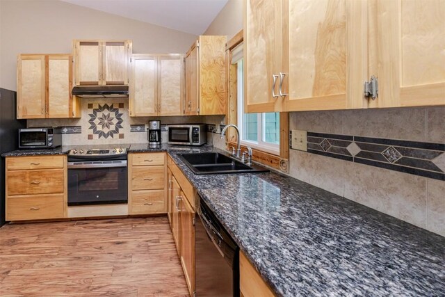 kitchen with stainless steel appliances, light brown cabinetry, a sink, vaulted ceiling, and under cabinet range hood