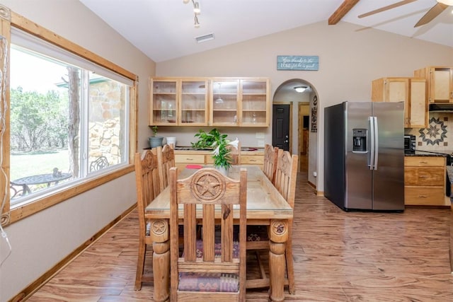 dining space with vaulted ceiling with beams, visible vents, arched walkways, and light wood-style floors