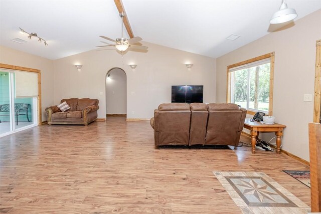 living room featuring arched walkways, light wood-style floors, baseboards, lofted ceiling with beams, and ceiling fan