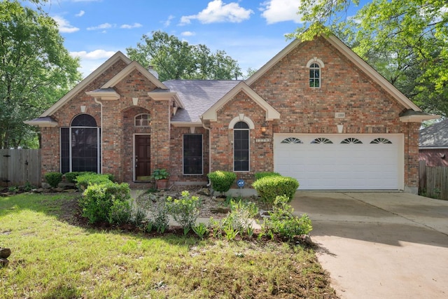 view of front of property featuring concrete driveway, fence, brick siding, an attached garage, and a front yard