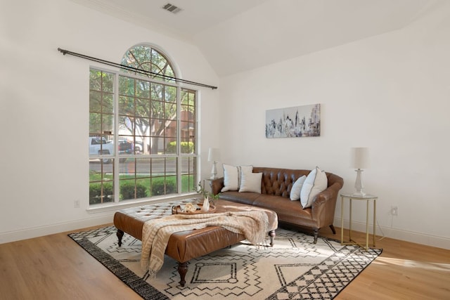 living room with vaulted ceiling, wood finished floors, visible vents, and plenty of natural light
