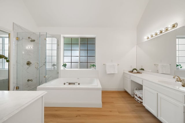 bathroom featuring a bath, a marble finish shower, lofted ceiling, wood finished floors, and vanity