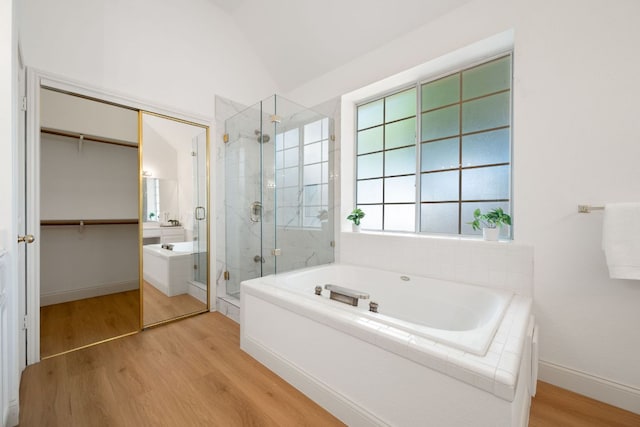 bathroom with lofted ceiling, a garden tub, wood finished floors, and a stall shower