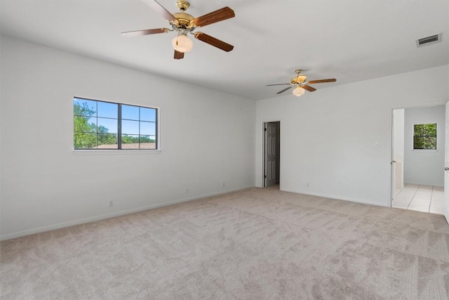spare room featuring a ceiling fan, a wealth of natural light, and light colored carpet