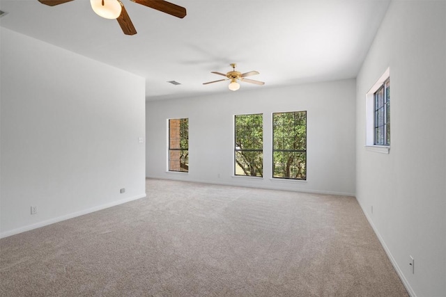 empty room featuring carpet floors, visible vents, baseboards, and ceiling fan