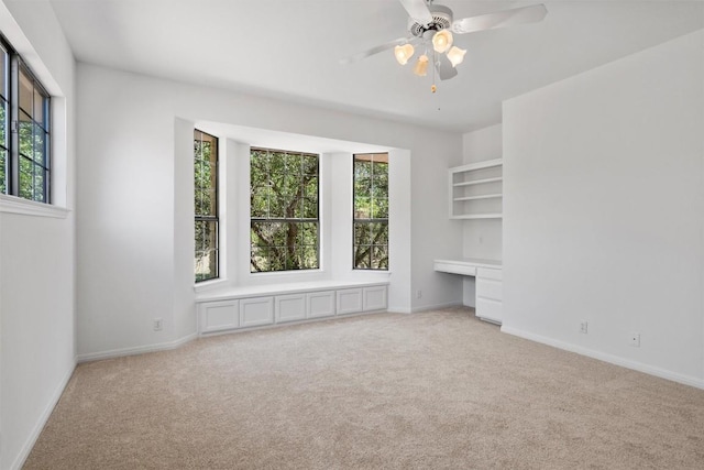 interior space with baseboards, a ceiling fan, built in study area, and carpet floors