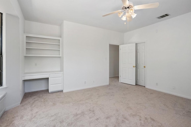 unfurnished bedroom featuring baseboards, carpet floors, visible vents, and built in desk