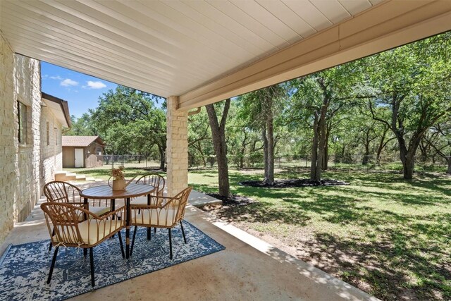 view of patio with fence, an outbuilding, and outdoor dining area