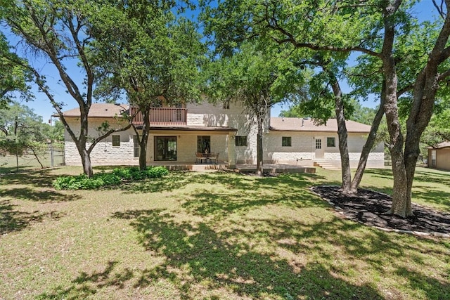 rear view of house with a balcony, a yard, and a patio