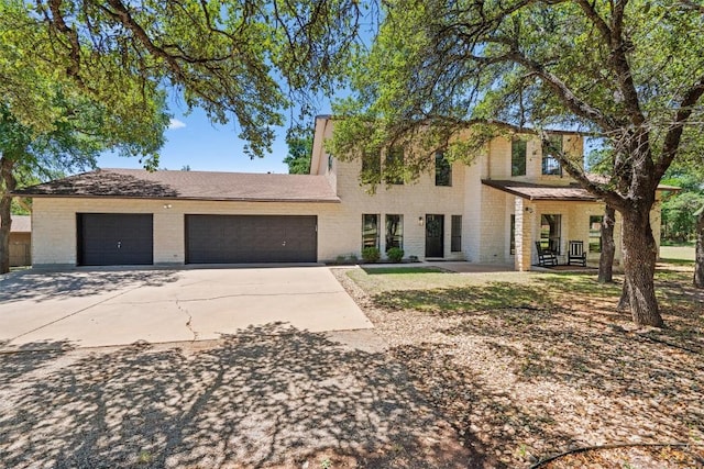 traditional-style house with driveway, brick siding, and a garage