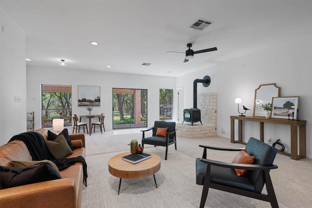 living area featuring a wood stove, visible vents, and light carpet