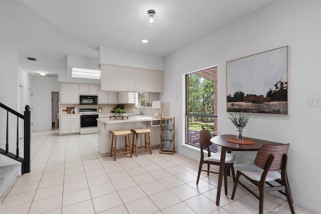 kitchen with a peninsula, electric range, visible vents, black microwave, and light countertops