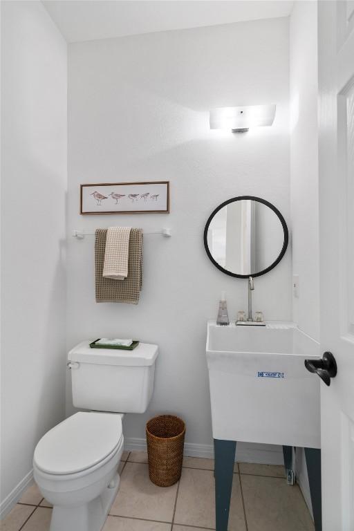 half bathroom featuring toilet, tile patterned floors, and baseboards