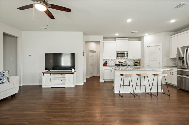 kitchen featuring stainless steel appliances, tasteful backsplash, open floor plan, visible vents, and a kitchen bar