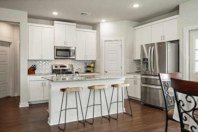 kitchen featuring dark wood finished floors, backsplash, appliances with stainless steel finishes, and a sink