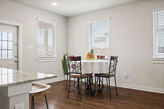 dining room featuring dark wood finished floors, baseboards, and a wealth of natural light