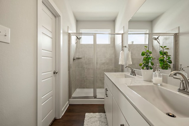 full bath featuring double vanity, a shower stall, wood finished floors, and a sink
