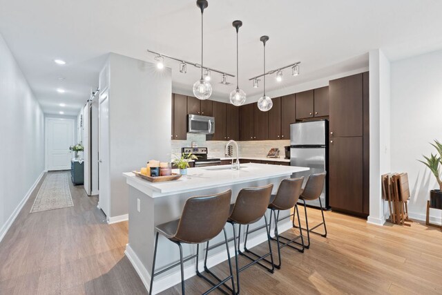 1900 Barton Springs Rd Unit 3007, Austin, TX 78704 - kitchen featuring appliances with stainless steel finishes, dark brown cabinetry, light wood-type flooring, light countertops, and recessed lighting