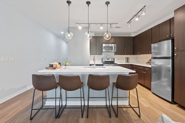 1900 Barton Springs Rd Unit 3007, Austin, TX 78704 - kitchen with appliances with stainless steel finishes, a sink, light wood-style floors, light countertops, and a breakfast bar