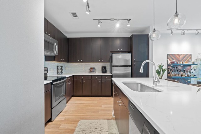 1900 Barton Springs Rd Unit 3007, Austin, TX 78704 - kitchen with appliances with stainless steel finishes, a sink, light wood-style floors, track lighting, and decorative backsplash