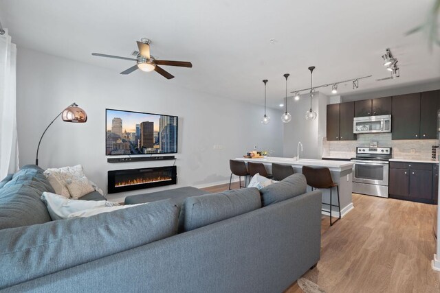 1900 Barton Springs Rd Unit 3007, Austin, TX 78704 - living room with light wood-style flooring, a glass covered fireplace, ceiling fan, track lighting, and baseboards