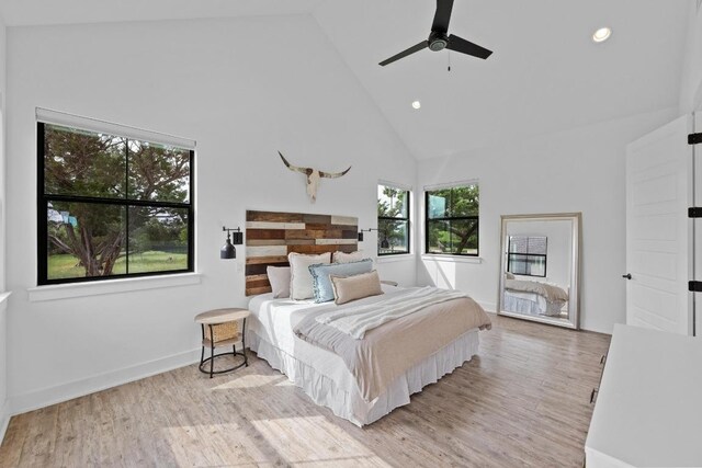 bedroom with recessed lighting, light wood-style flooring, baseboards, and high vaulted ceiling