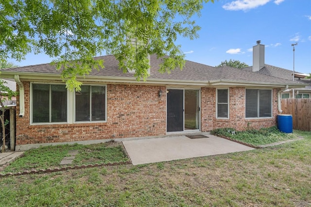 back of house with fence, a chimney, brick siding, and a patio