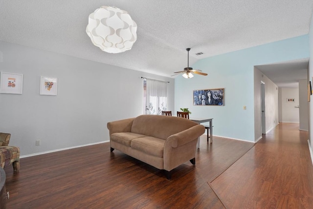 living room with visible vents, a ceiling fan, baseboards, a textured ceiling, and dark wood-style flooring