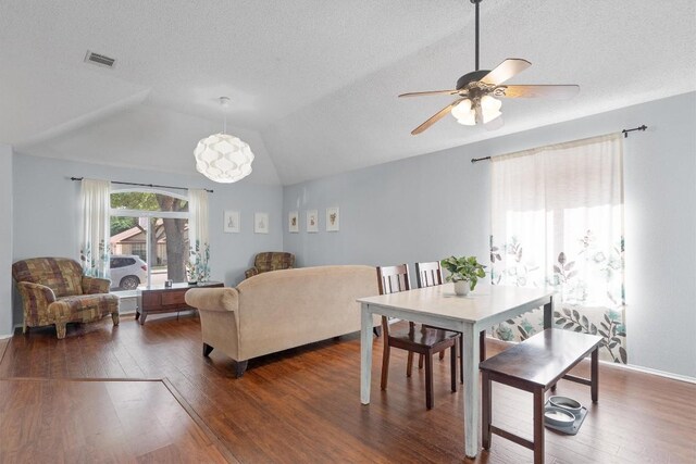 dining space featuring a ceiling fan, lofted ceiling, dark wood-style flooring, and visible vents